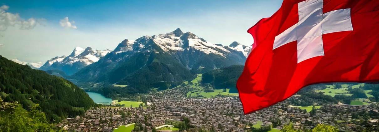 Landschaftsbild von einer Stadt im Tal und Berge und ein See im Hintergrund. Im Vordergrund eine schweizer Flagge. Dieses Bild wurde mit KI generiert.